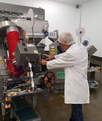 Engineer servicing a labelling machine on a production line